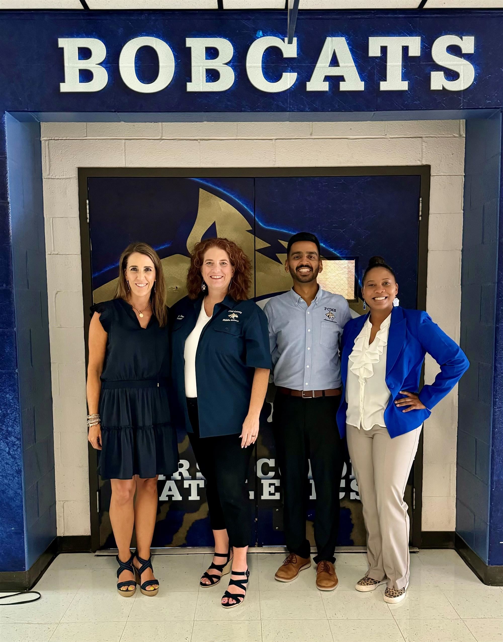 FCMS Admin Team in front of Bobcats signage